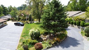A parking lot with a grassy area and a tree, surrounded by residential buildings. - Alpine Village Inn (Blowing Rock)