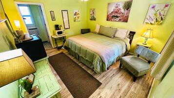 Een slaapkamer met een bed, nachtkastje, lamp en een plafondventilator.
