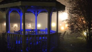 A gazebo with a blue-lit interior, surrounded by a wooden deck and a foggy outdoor setting. - Alpine Village Inn (Blowing Rock)