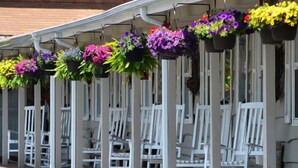 A building with a porch decorated with hanging flower baskets. - Alpine Village Inn (Blowing Rock)