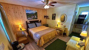 A cozy room with a bed, a desk, a chair, a ceiling fan, and a small kitchenette. - Alpine Village Inn (Blowing Rock)
