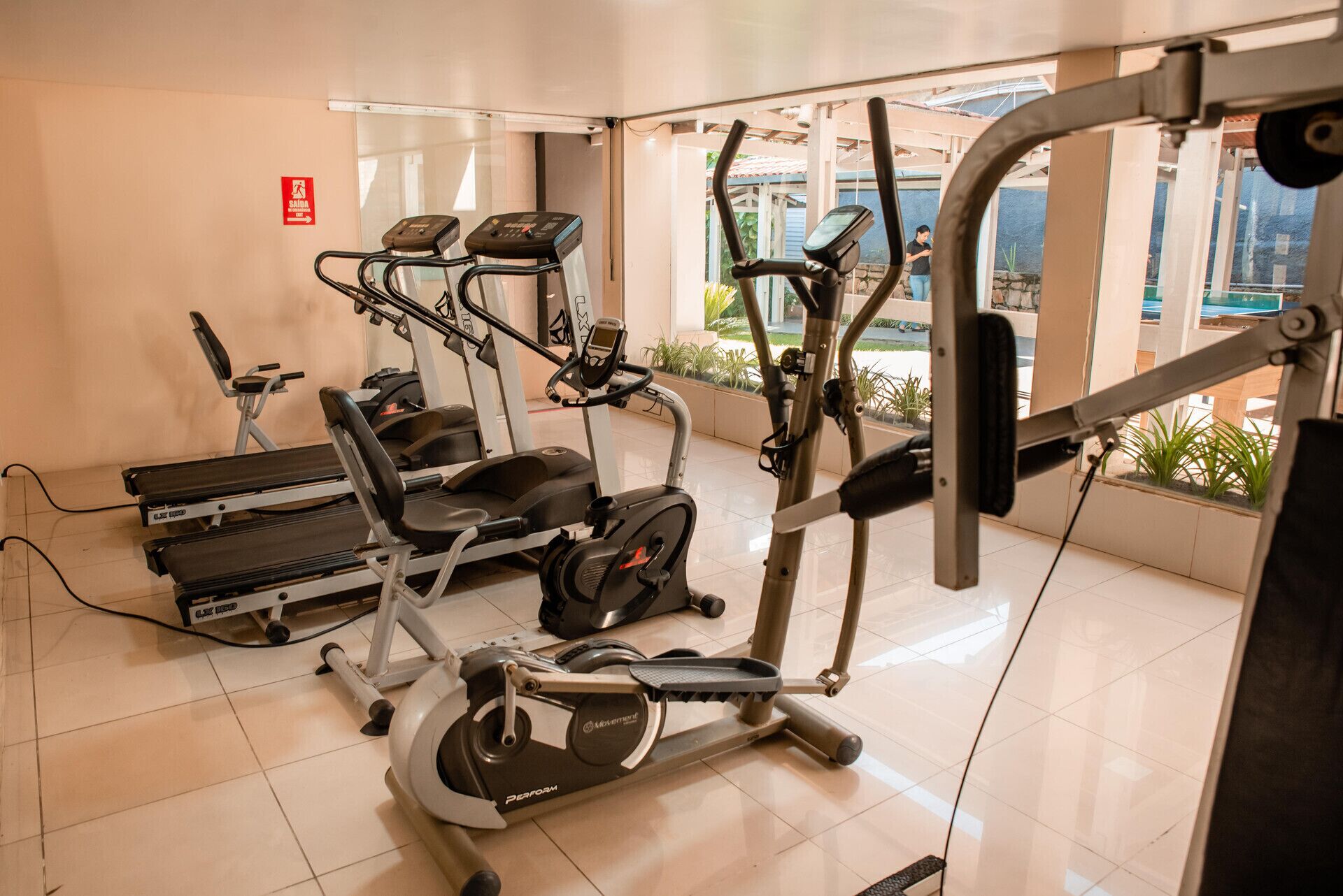 Een fitnessruimte met diverse trainingsapparaten, waaronder loopbanden, een elliptische trainer en gewichtmachines.