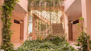 A corridor with a central staircase surrounded by lush greenery and a skylight above. - Hotel Village Premium Caruaru (Caruaru)