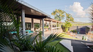 A covered outdoor seating area with modern furniture, a pool, and a view of the landscape. - Hotel Village Premium Caruaru (Caruaru)