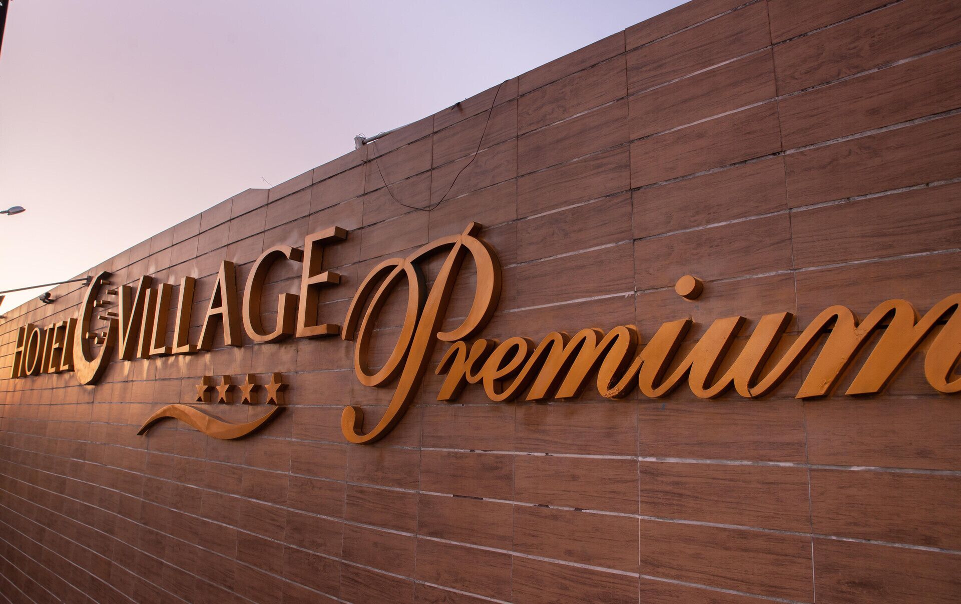Pared de madera con el texto "Hotel Village Premium" y estrellas decorativas.