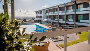 A modern hotel with a rooftop pool, outdoor seating, and a view of the cityscape. - Hotel Village Premium Caruaru (Caruaru)