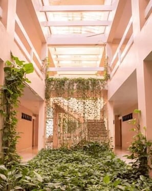A corridor with a central staircase surrounded by lush greenery.