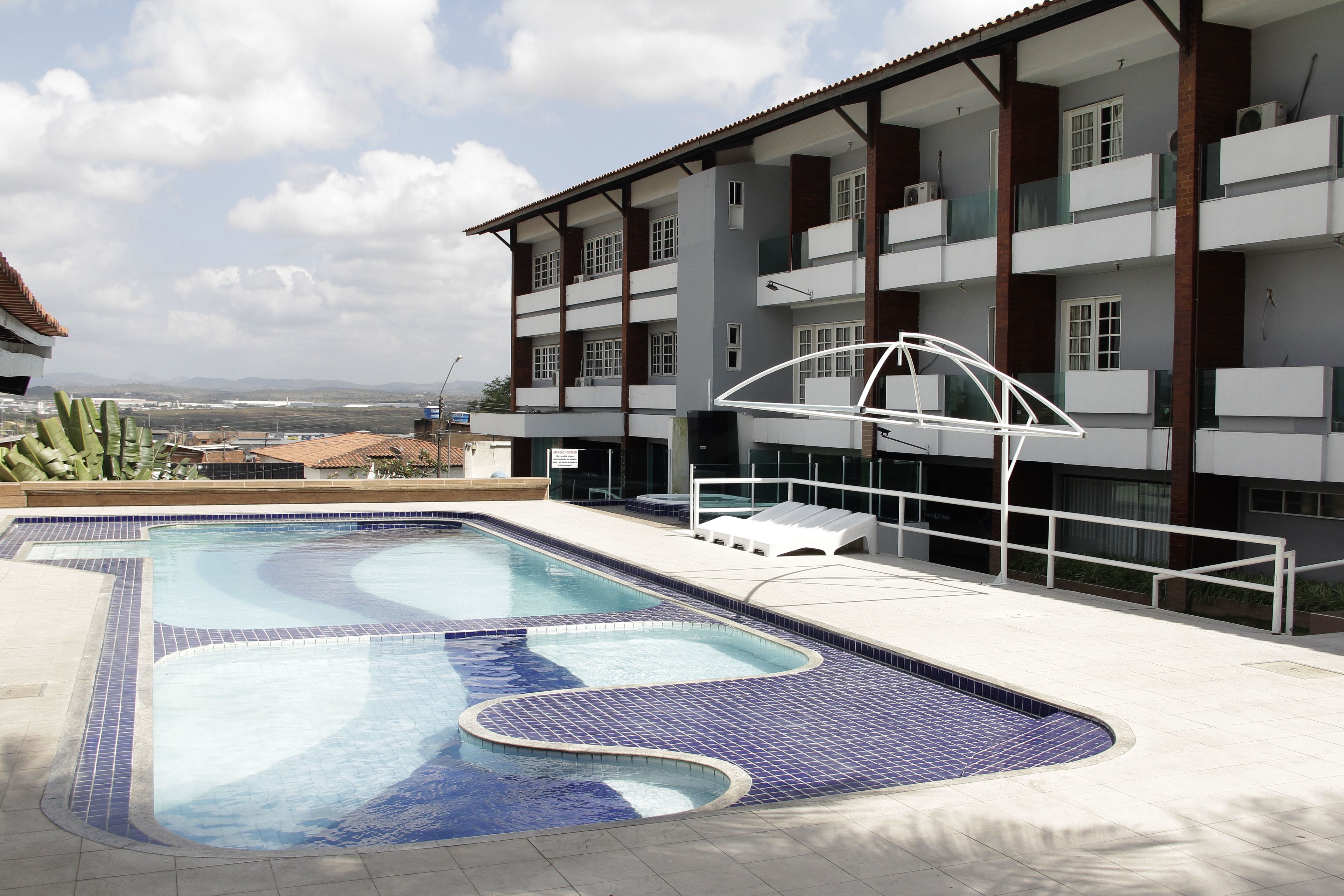 Una piscina de diseño curvo, rodeada por un solárium con baldosas.