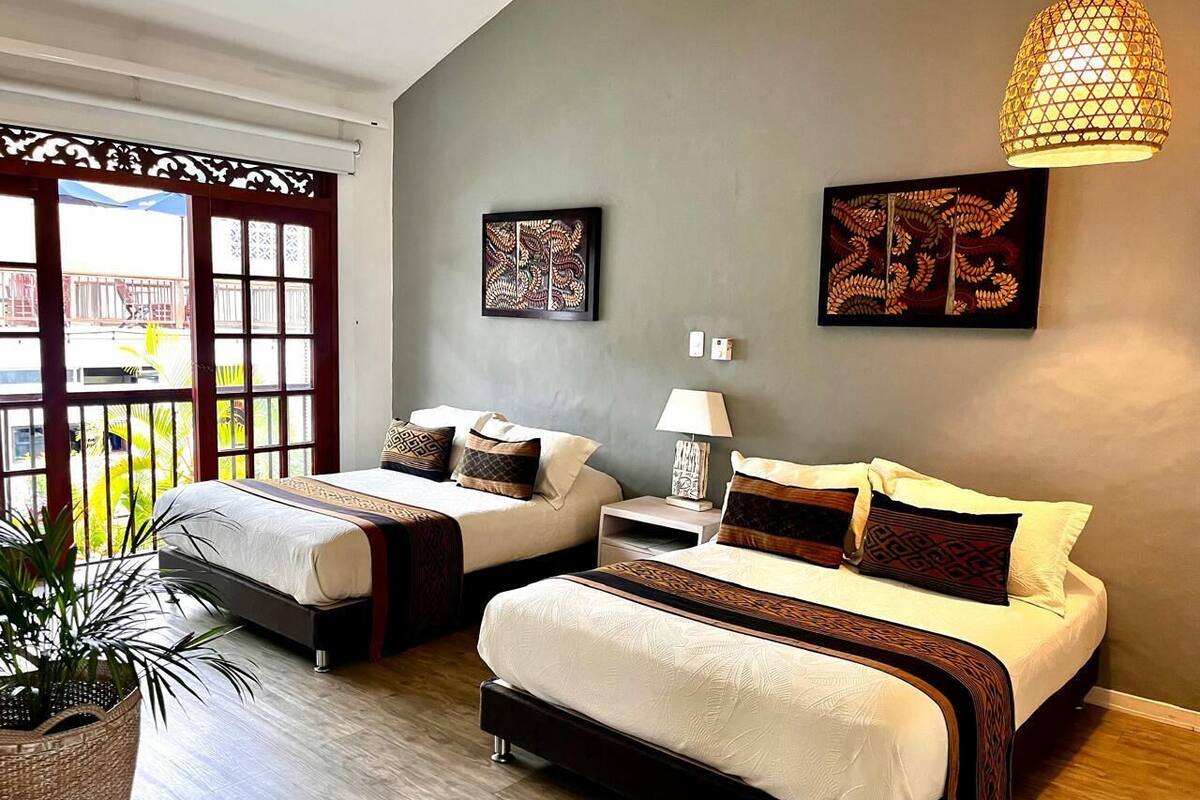 Une chambre d’hôtel avec deux lits, une grande fenêtre donnant sur un beau paysage et un élément décoratif mural.