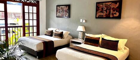 A hotel room with two beds, a large window with a view, and a decorative wall piece.