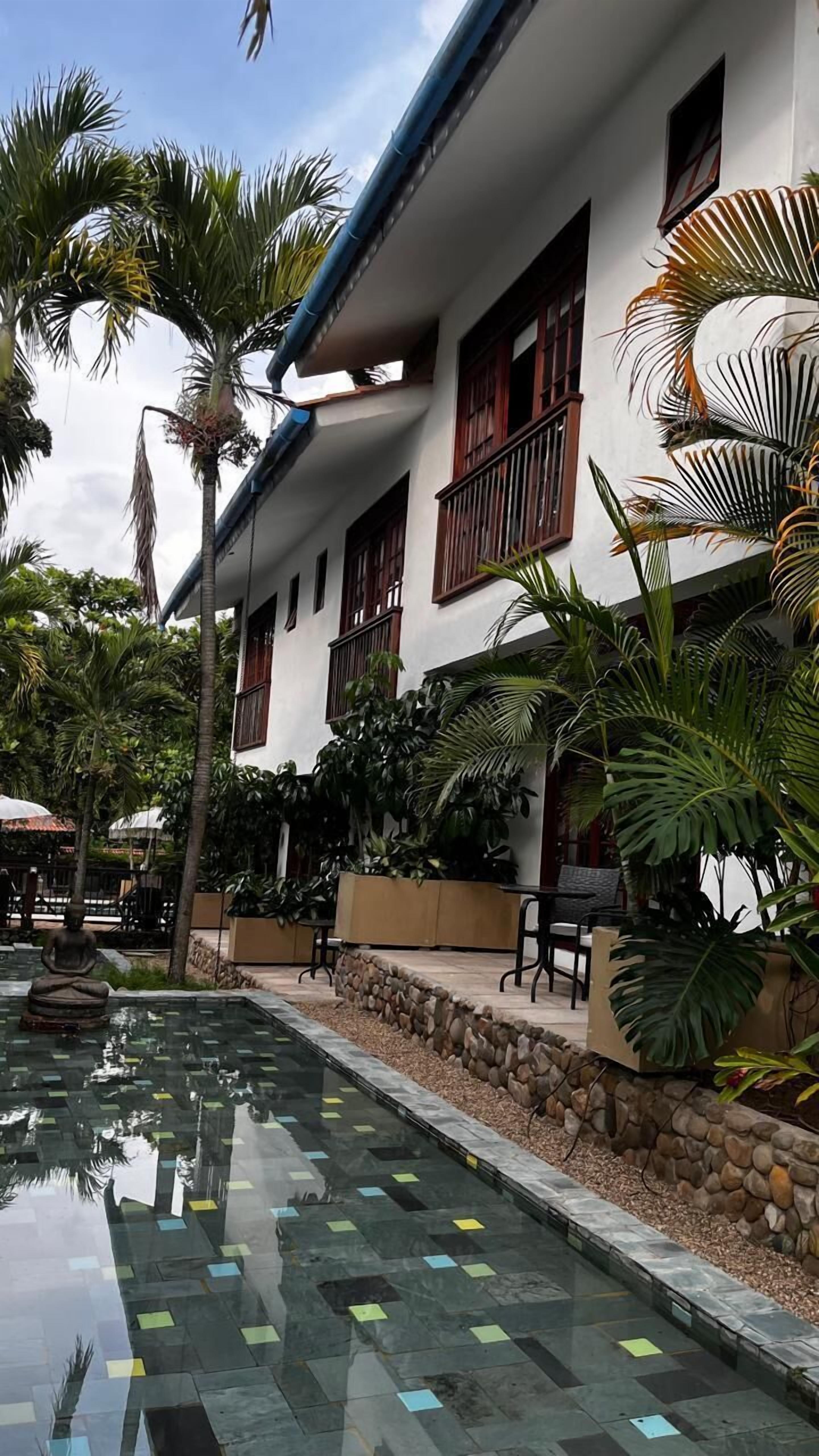 Ein Gebäude mit Pool, umgeben von Palmen und Pflanzen.