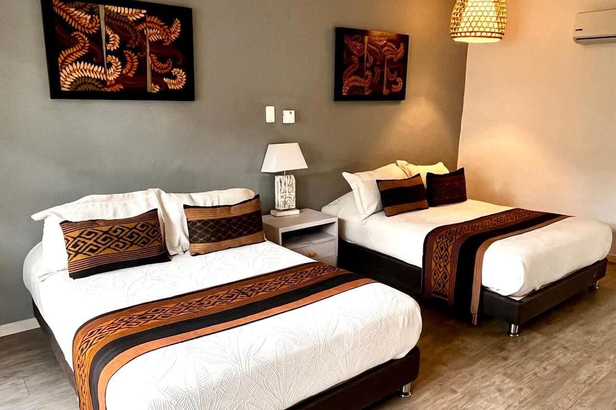 Une chambre d’hôtel avec deux lits, une table de chevet, une lampe et des œuvres d’art accrochées aux murs.