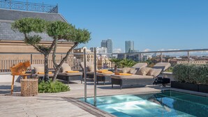 A rooftop pool area with lounge chairs, a small table, and a basket. - Serras Barcelona (Barcelona)