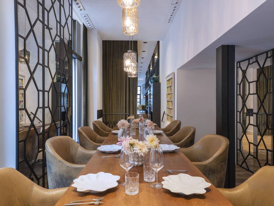 Una larga mesa de comedor dispuesta con sillas, centros de mesa y una araña.
