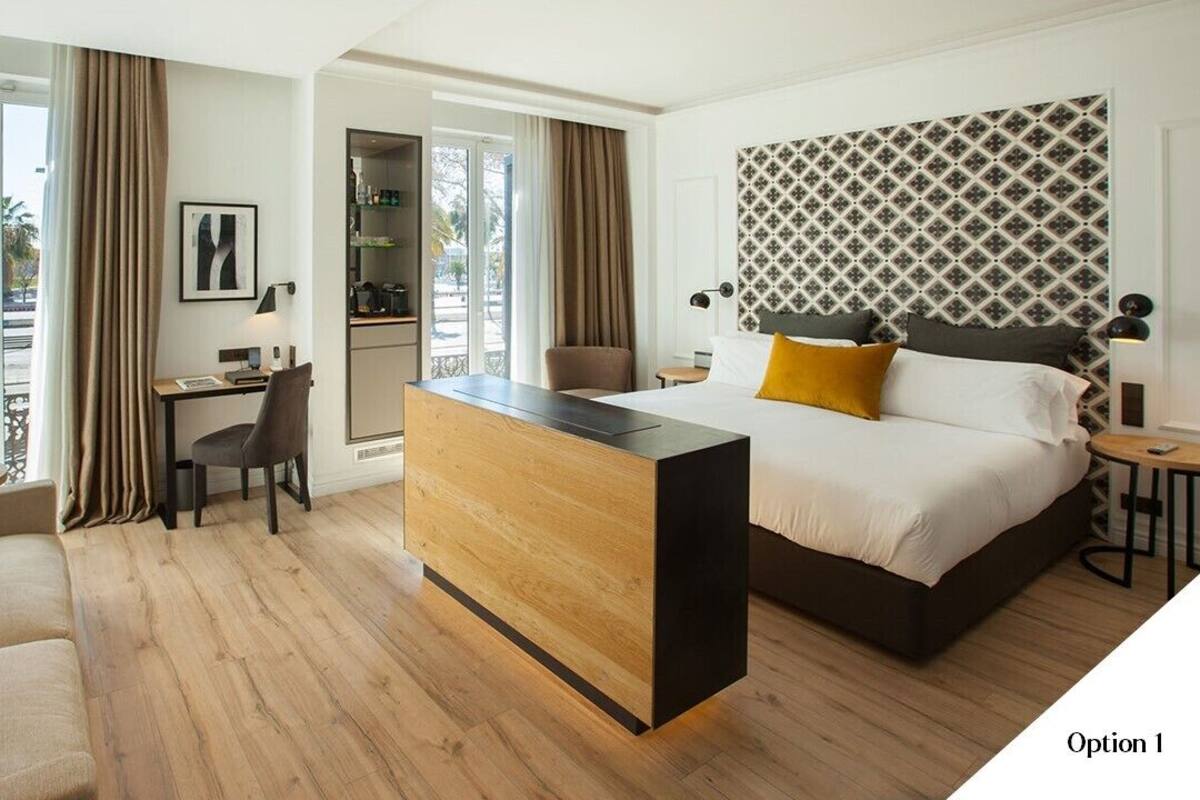 A hotel room with a bed, a desk, a sofa, and a view of the outdoors.
