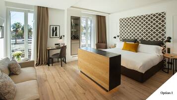 Habitación de hotel con cama, escritorio, sofá y vistas al exterior.