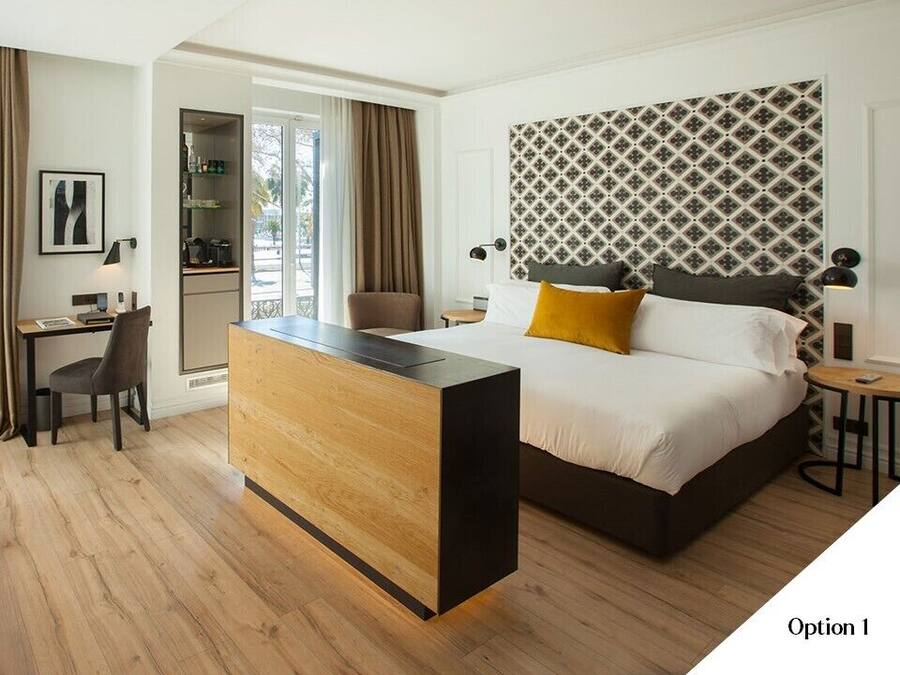 Habitación de hotel con cama, escritorio, sofá y vistas al exterior.