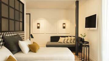 A modern hotel room with a large bed, a sofa, and a TV mounted on the wall.