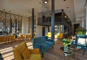 A spacious living area with a blue sofa, yellow chairs, and a dining area with yellow chairs. - Serras Barcelona (Barcelona)