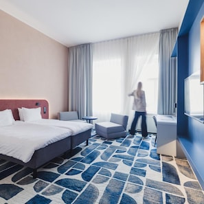 A hotel room with a bed, a desk, a chair, and a large window with curtains. - Hotel London Tartu (Tartu)