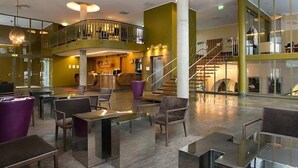 A spacious lobby with a central bar area, multiple seating options, and a staircase leading to an upper level. - Hotel London Tartu (Tartu)