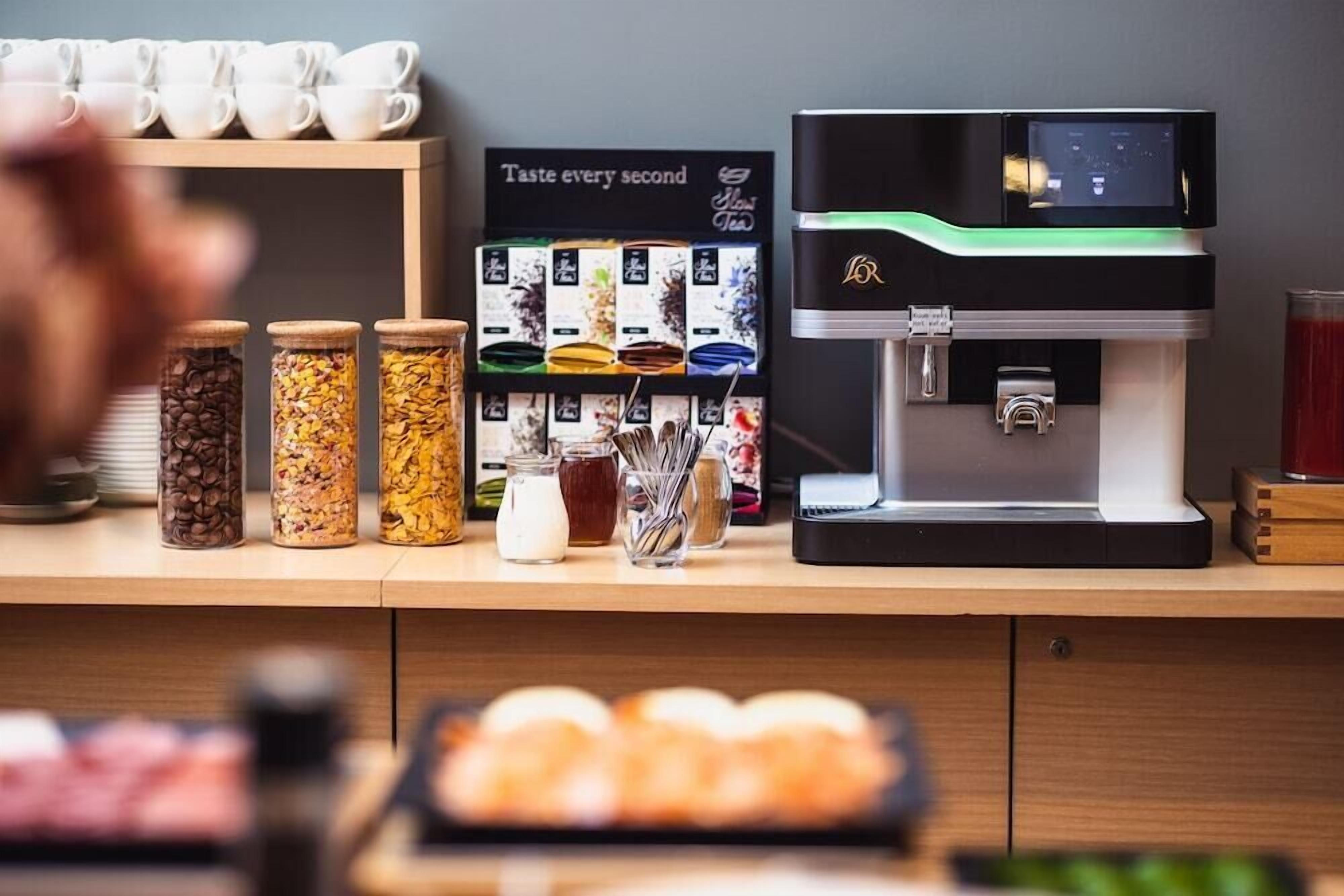 Un espace dédié au café, comprenant une machine à café, des bocaux remplis de grains de café et un tableau affichant le menu.