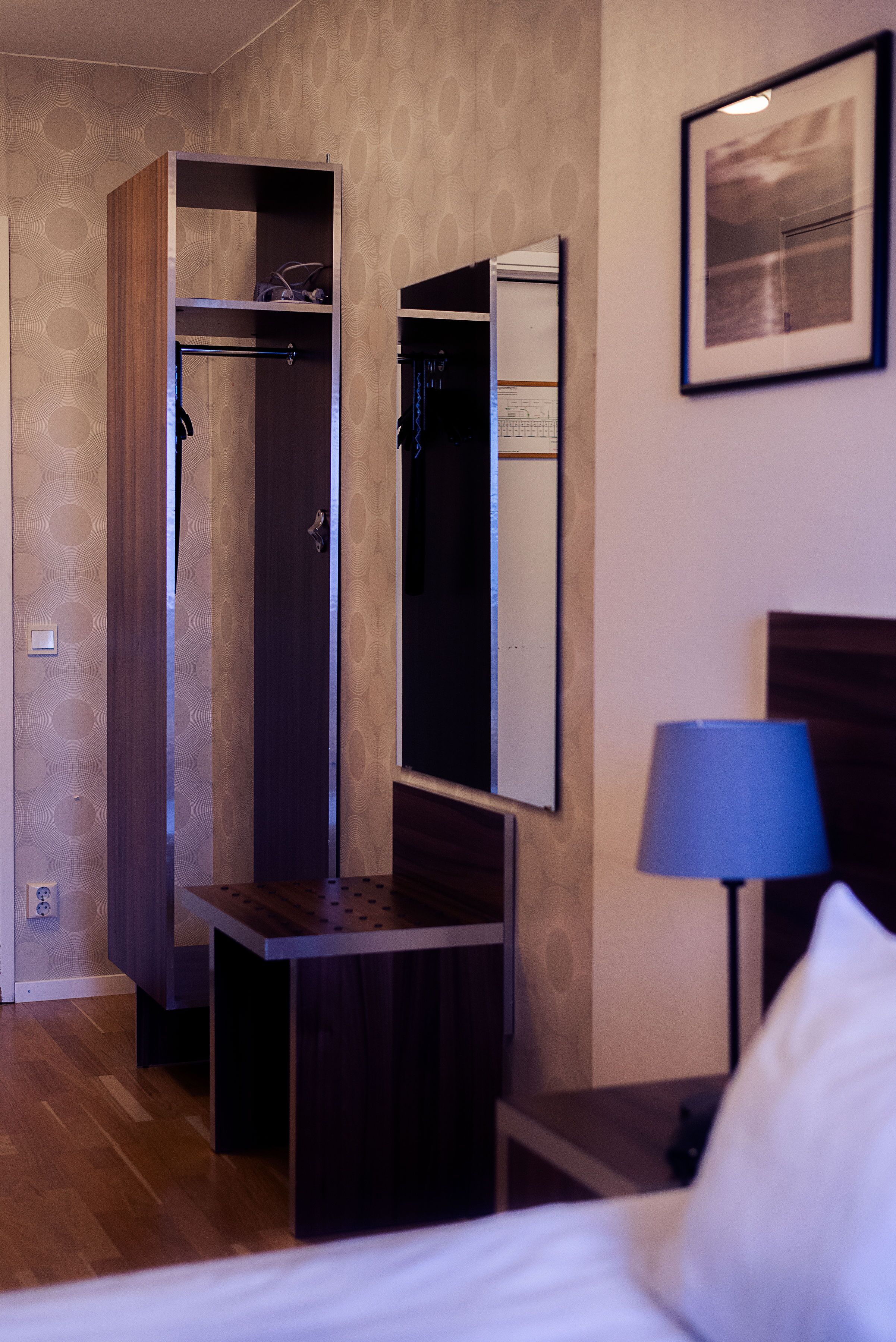 Une chambre d’hôtel comprenant un lit, un bureau, une armoire, un miroir et une lampe.