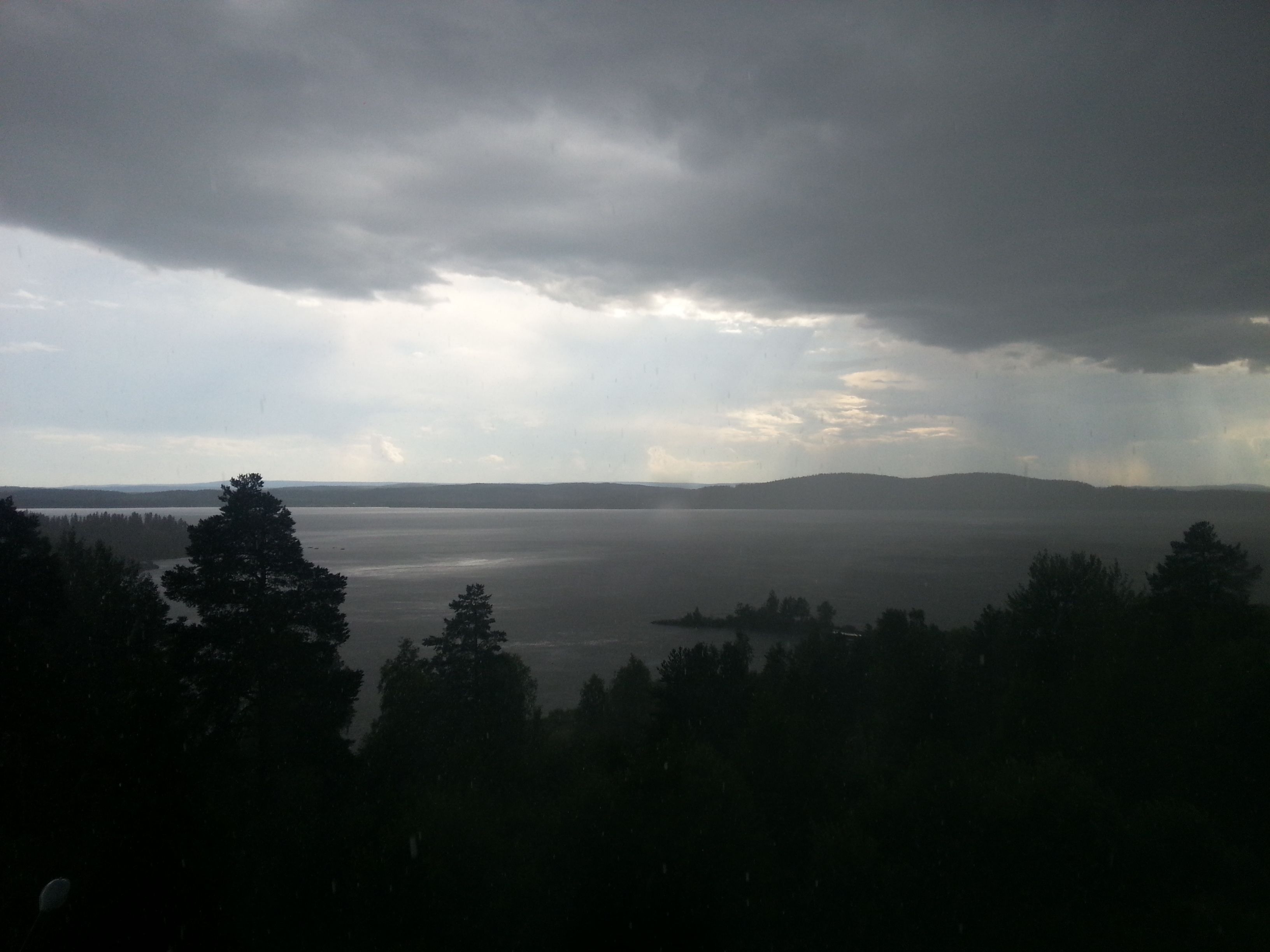 Ein See mit umliegenden Hügeln und Bäumen.