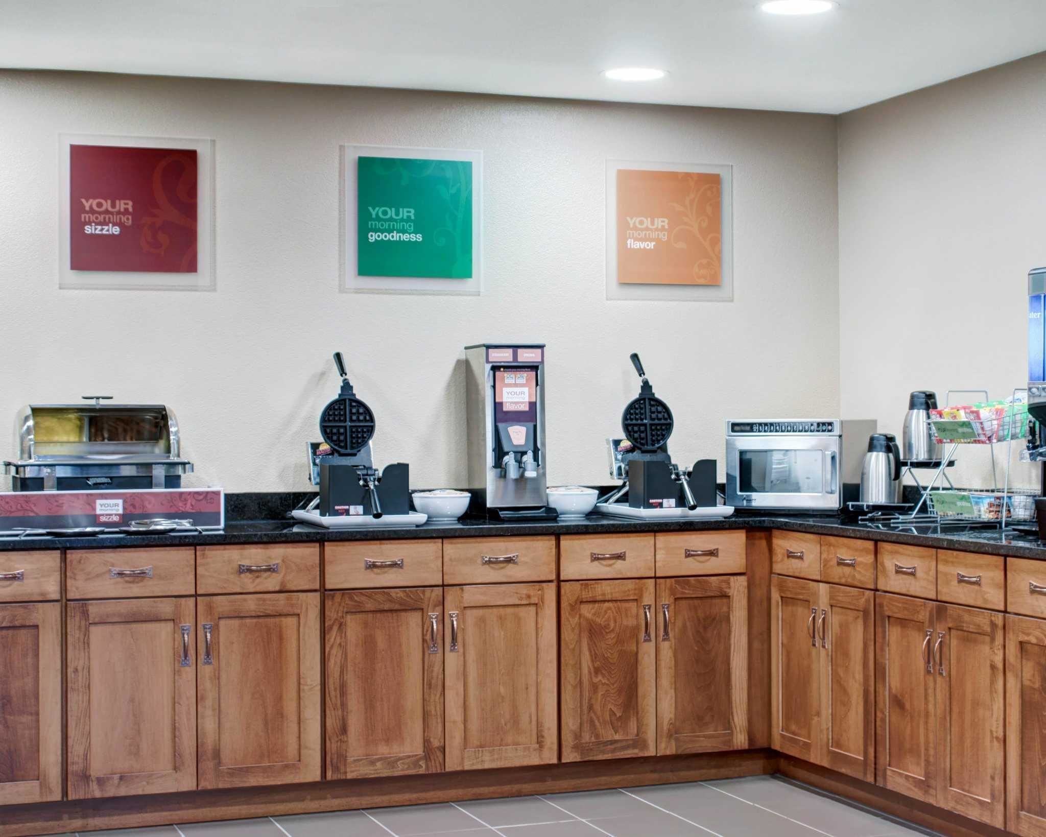 A breakfast bar with waffle makers, a coffee machine, and a microwave.
