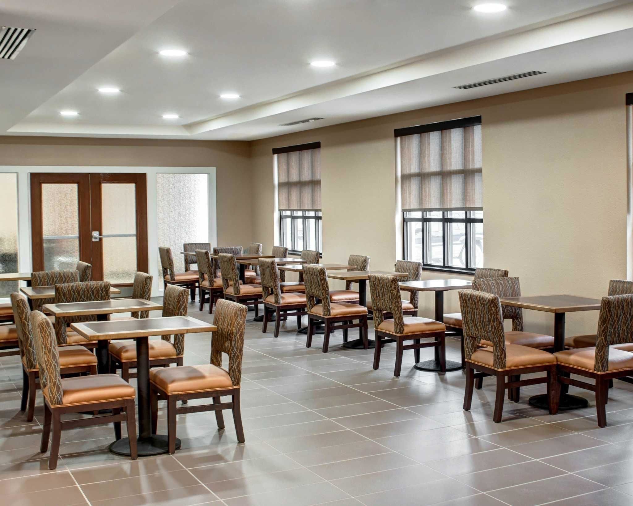 A spacious dining area with multiple tables and chairs, large windows, and a clean, modern design.