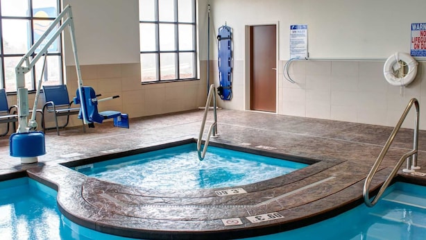 An indoor swimming pool with a lifeguard chair, a blue lifebuoy, and a sign indicating no lifeguard on duty.
