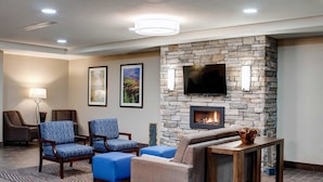 A modern lounge area with a stone fireplace, comfortable seating, a flat-screen TV, and a decorative vase.