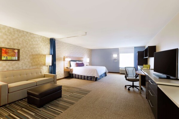 Una habitación de hotel con una cama, un escritorio con ordenador, un sofá y una televisión.