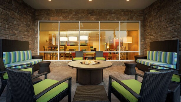 An outdoor seating area with wicker furniture and a central fire pit. - Home2 Suites by Hilton Midland (Midland)
