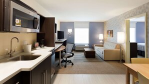 A modern hotel room with a kitchenette, a sofa, a desk, and a bed. - Home2 Suites by Hilton Midland (Midland)