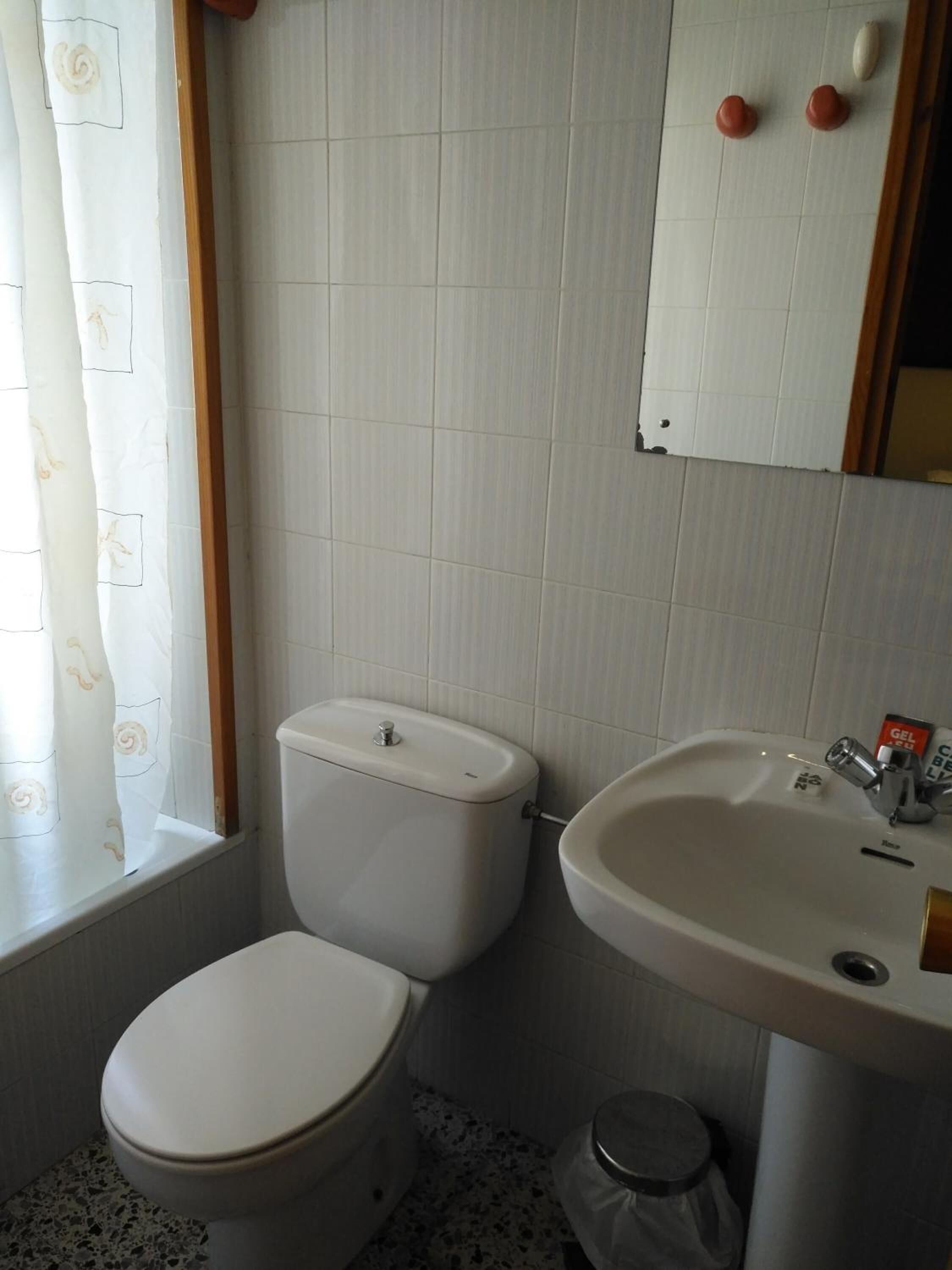Une salle de bain avec des toilettes, un lavabo et un miroir.