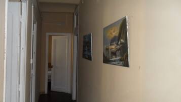 A narrow hallway with white doors and a dark floor. There are two framed pictures on the wall.