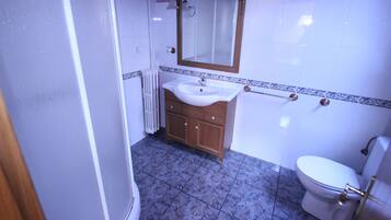 Une salle de bain avec un lavabo blanc, un meuble-lavabo en bois et des toilettes.