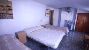 Una habitación con dos camas, un armario de madera, un radiador y un televisor en la pared.