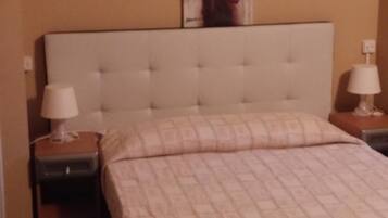Une chambre d’hôtel avec un grand lit, deux tables de chevet avec des lampes, un tableau au mur et une télécommande sur le lit.