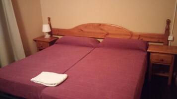 Una cama doble con cabecera de madera, dos mesitas de noche y una toalla blanca doblada sobre la cama.