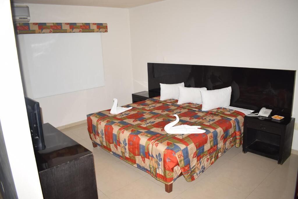 A hotel room with a bed, a TV, a desk, and a telephone.