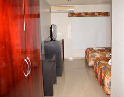 Una habitación de hotel con escritorio, televisión, cama con colcha colorida y armario.