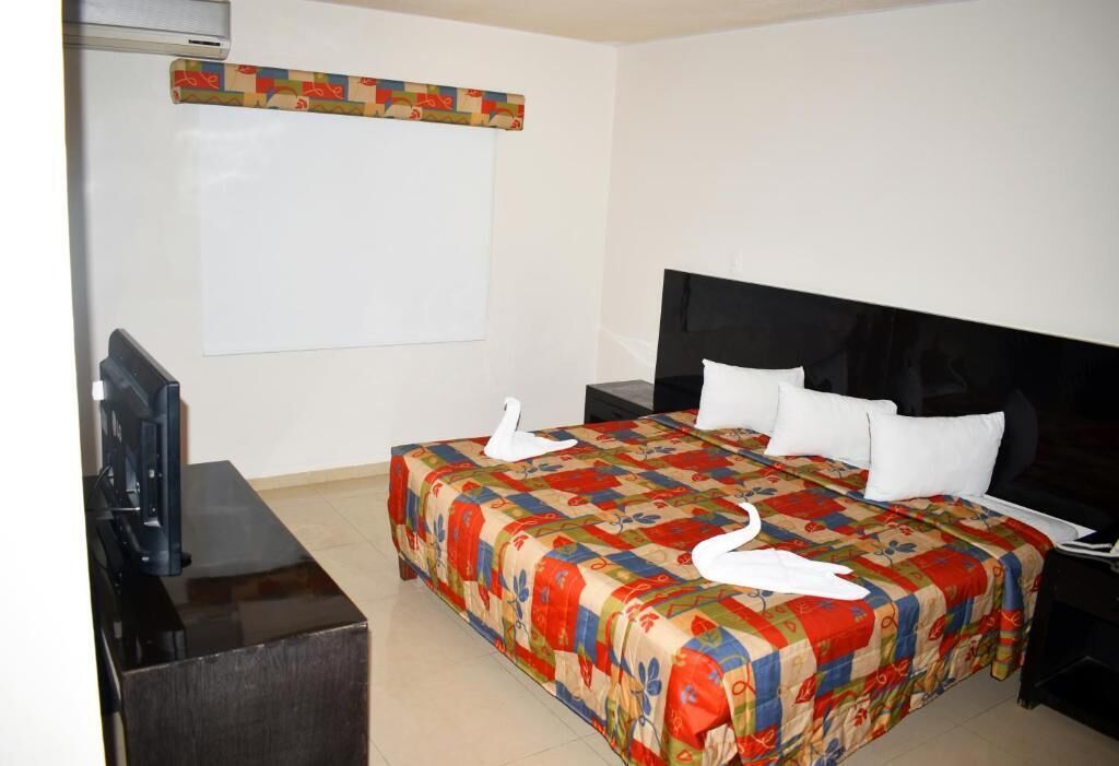Een hotelkamer met een bed, een televisie, een bureau en een whiteboard.
