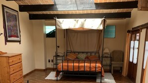 A bedroom with a four-poster bed, a wooden dresser, a chair, and a window with curtains. - Kukurutz Residencia (San Cristóbal de las Casas)