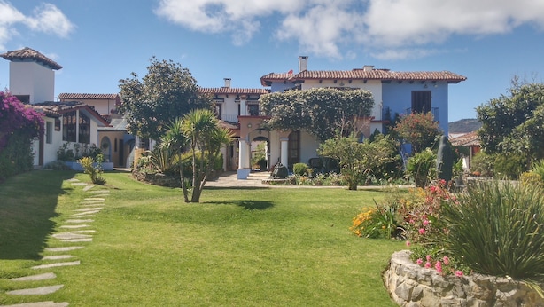 A courtyard with a stone pathway leading to a building with a tiled roof and columns. - Kukurutz Residencia (San Cristóbal de las Casas)