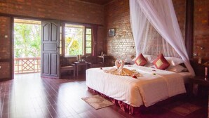 A bedroom with a large bed, a canopy, and a view of greenery outside. - Riverside @ Hsipaw Resort (Hsipaw)