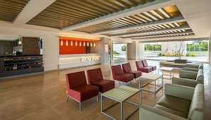 A hotel lobby with a reception desk, seating area, and a view of the outdoors.