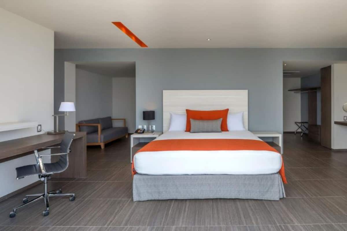 A modern hotel room with a large bed, a desk, and a chair.