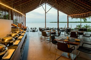 A restaurant with a buffet, outdoor seating, and a view of the sea.